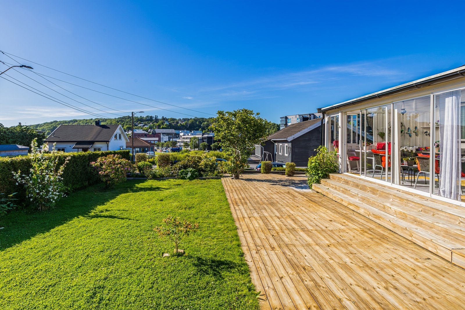 Terrasse i treverk på ca 83 m2 utenfor stuen og med utgang til hagen. Galleribilde