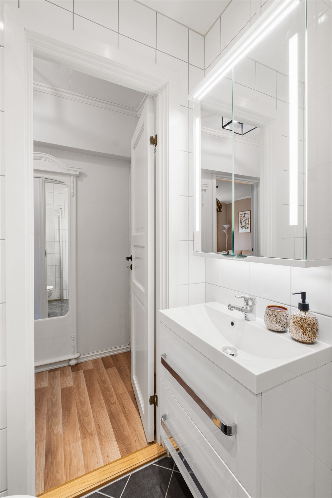 Badet er utstyrt med vegghengt klosett, servant i innredning, speilskap m/lys og dusjhjørne med svingbare glassdører. Opplegg for vaskemaskin. Galleribilde