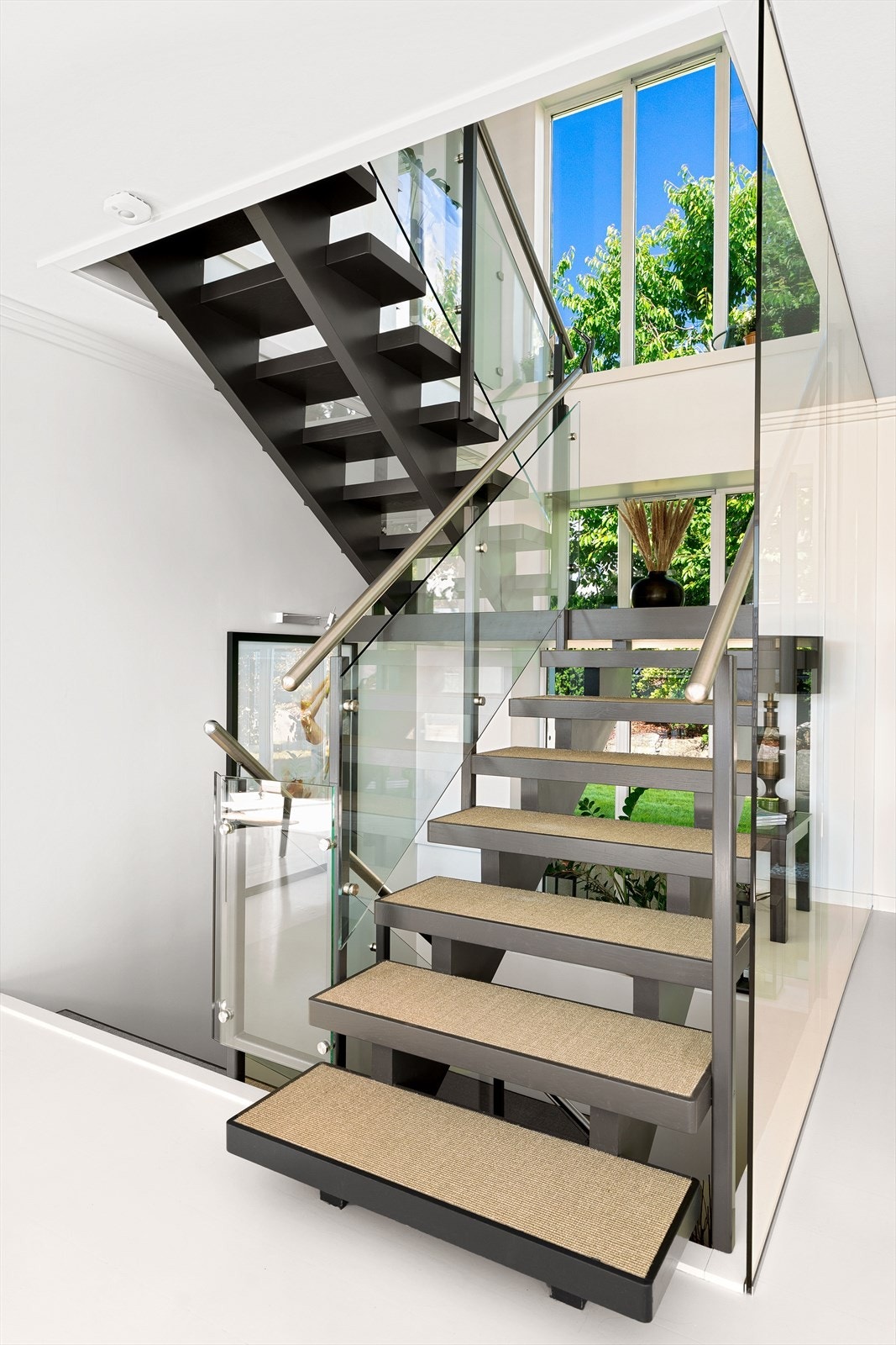 Meget delikat tretrapp med sisal teppe i trinn og glassrekkverk. De store vindusflatene i bakkant gir godt med naturlig lys. Galleribilde