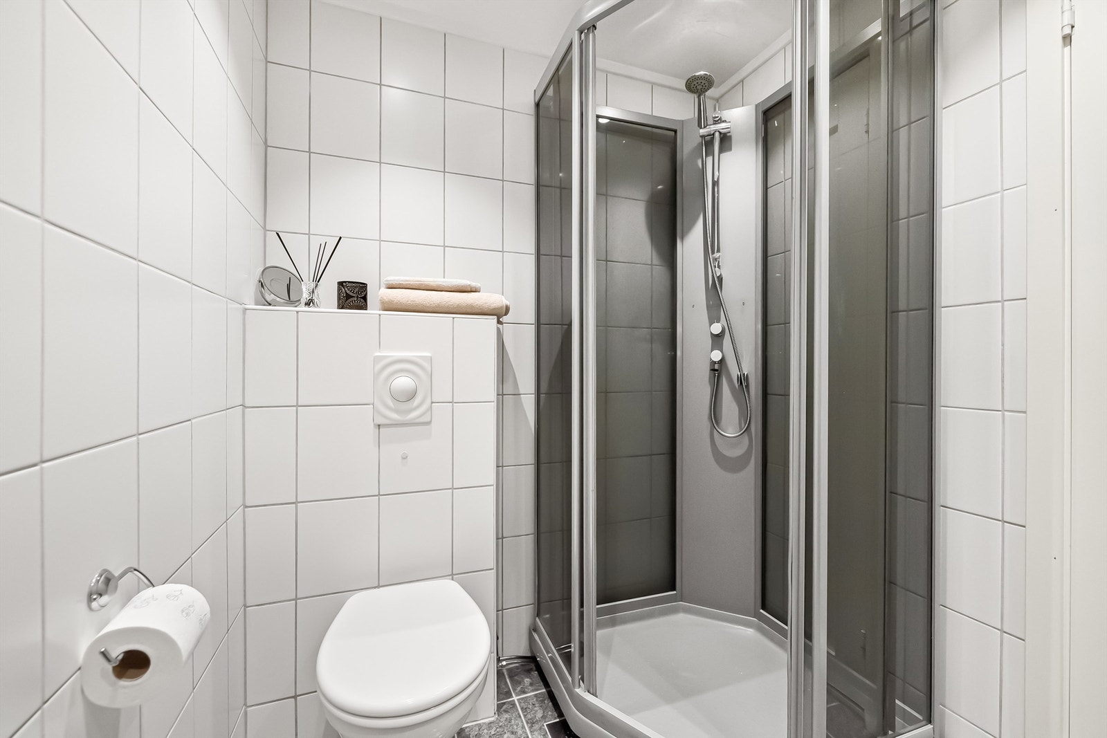 Badet inneholder servant med ett-greps blandebatteri, dusjkabinbett og vegghengt toalett. Galleribilde