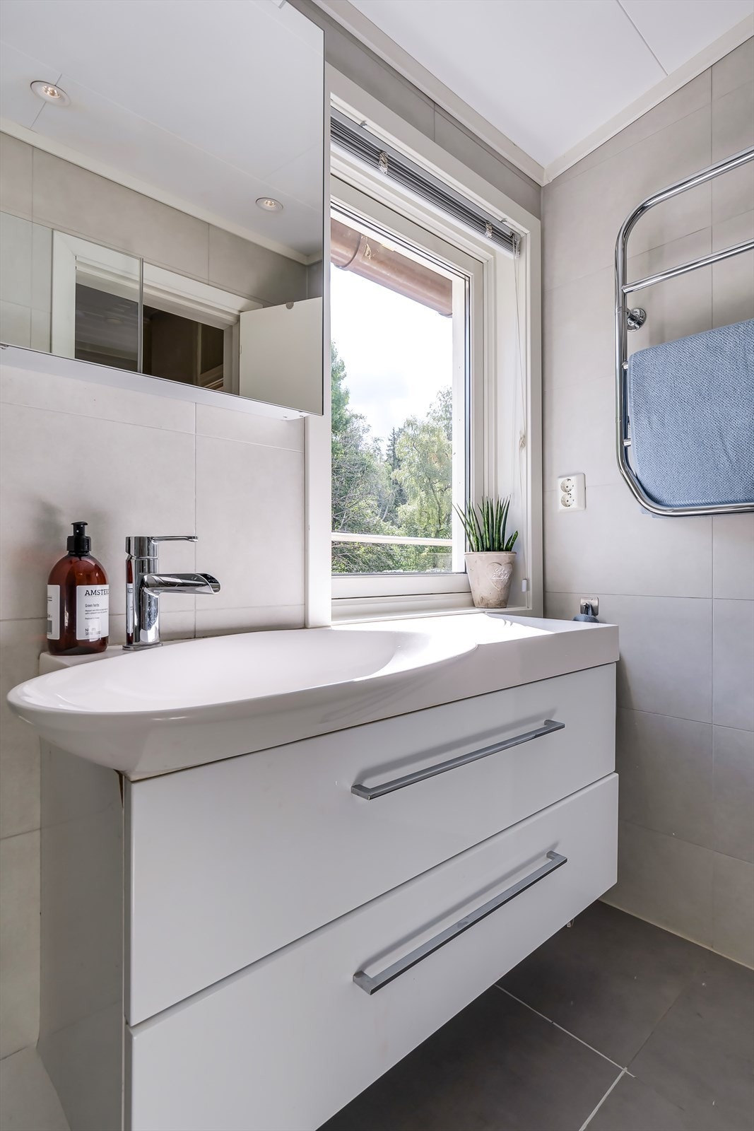Badet har elektriske varmekabler, dusj bak glassvegg og servant på stort benkeskap med skuffer. Galleribilde