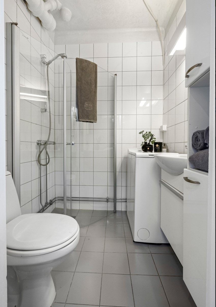 Flislagt bad med wc, dusjnisje, vaskemaskin og servant samt oppbevaringsplass. Galleribilde