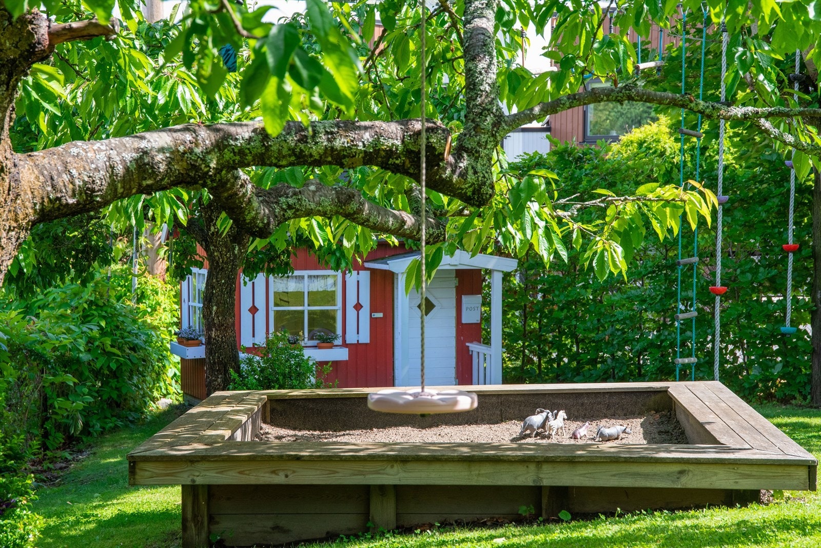 Nederst på tomten er det barnas avdeling med sandkasse, dukkestue, huske og klatretau. Galleribilde