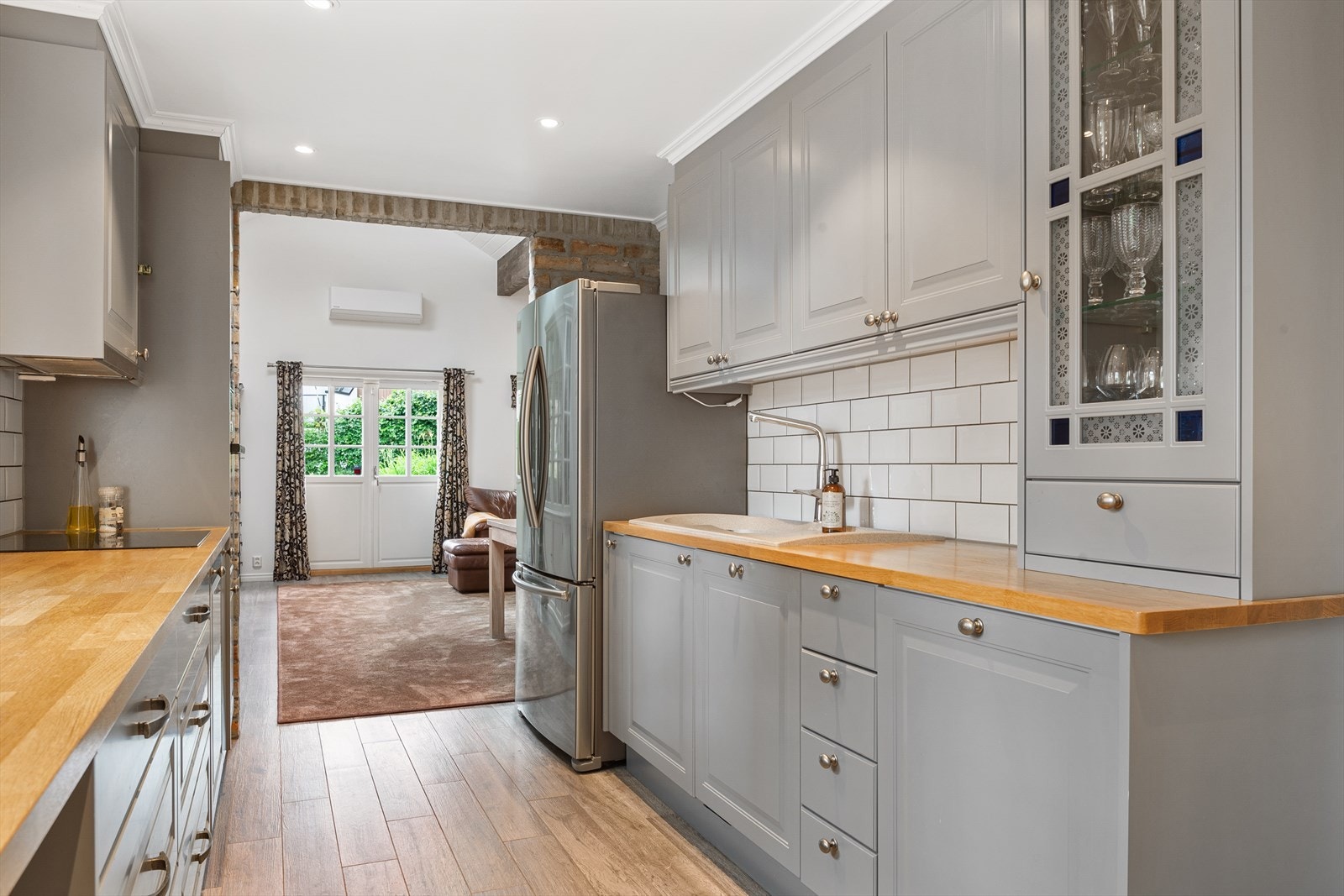 Kjøkkenet ligger i delvis åpen løsning mot stuen, noe som gir god kontakt mellom rommene. Kjøkkeninnredningen er fra ca. 2014 med grå, profilerte fronter og heltre benkeplate. Galleribilde