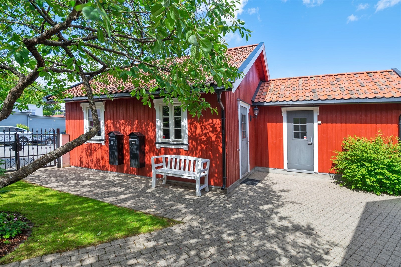 Tomten har en tofløyet smijernsport og steingjerde ut mot asfaltert innkjørsel. Galleribilde