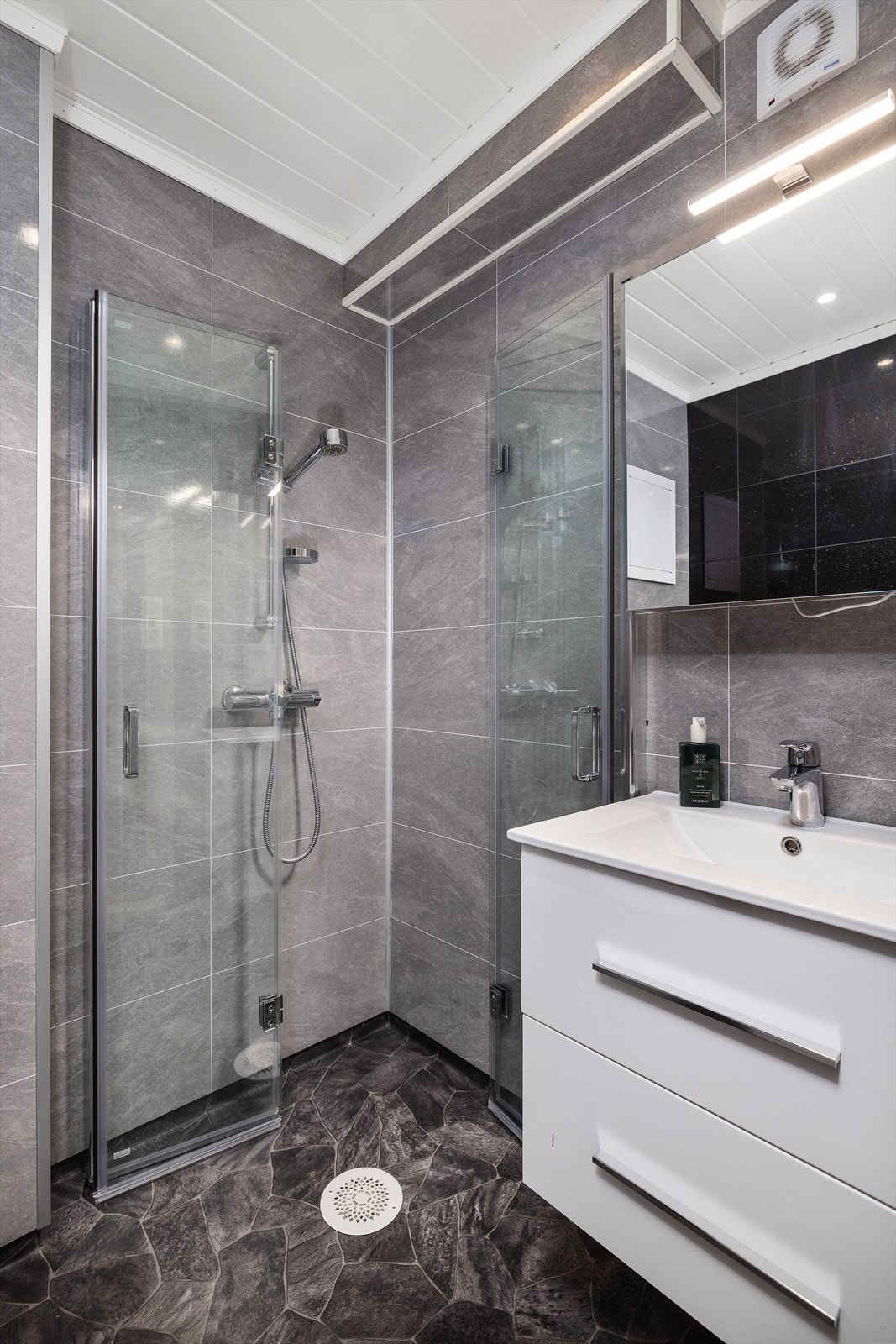 Badet har varme i gulv, bevegelige dusjvegger, lys og pen baderomsinnredning Galleribilde