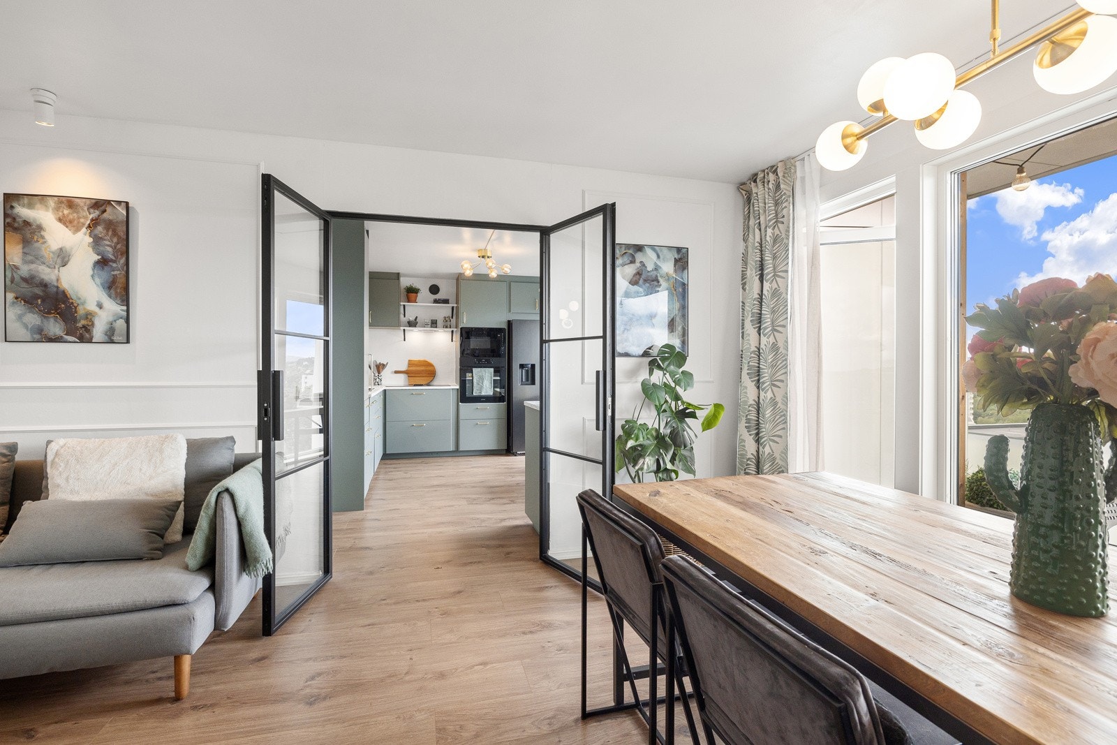 Stue og kjøkken i en sosial og delvis åpen løsning. Lekker tofløyet smijernsdør med glassfelter mellom rommene. Galleribilde