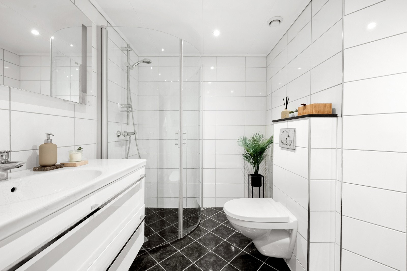 Badet er innredet med baderomsinnredning, vegghengt toalett, dusj med glassdører og ett høyskap. Galleribilde