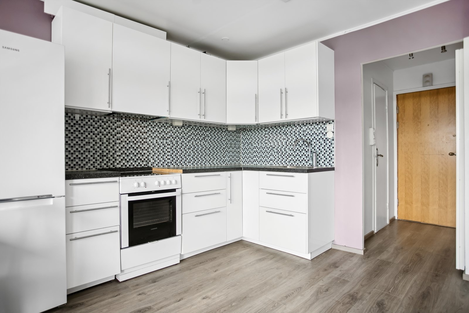 IKEA kjøkkeninnredning med hvite glatte fronter, benkeplater i laminat, rustfri oppvaskkum og ventilator med kullfilter. Galleribilde