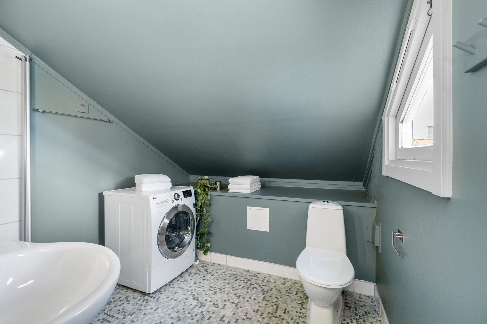 Bad med fliser på gulv og varmekabler. Badet er praktisk innredet. Rommet har et lite vindu som sørger for naturlig sollys, samt muligheter for naturlig lufting Galleribilde