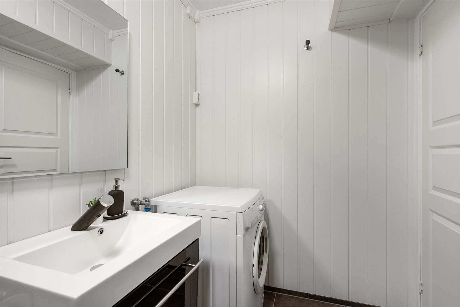 Badet er utstyrt med servantskap, gulvstående toalett, dusjkabinett og opplegg for både vaskemaskin og tørketrommel Galleribilde