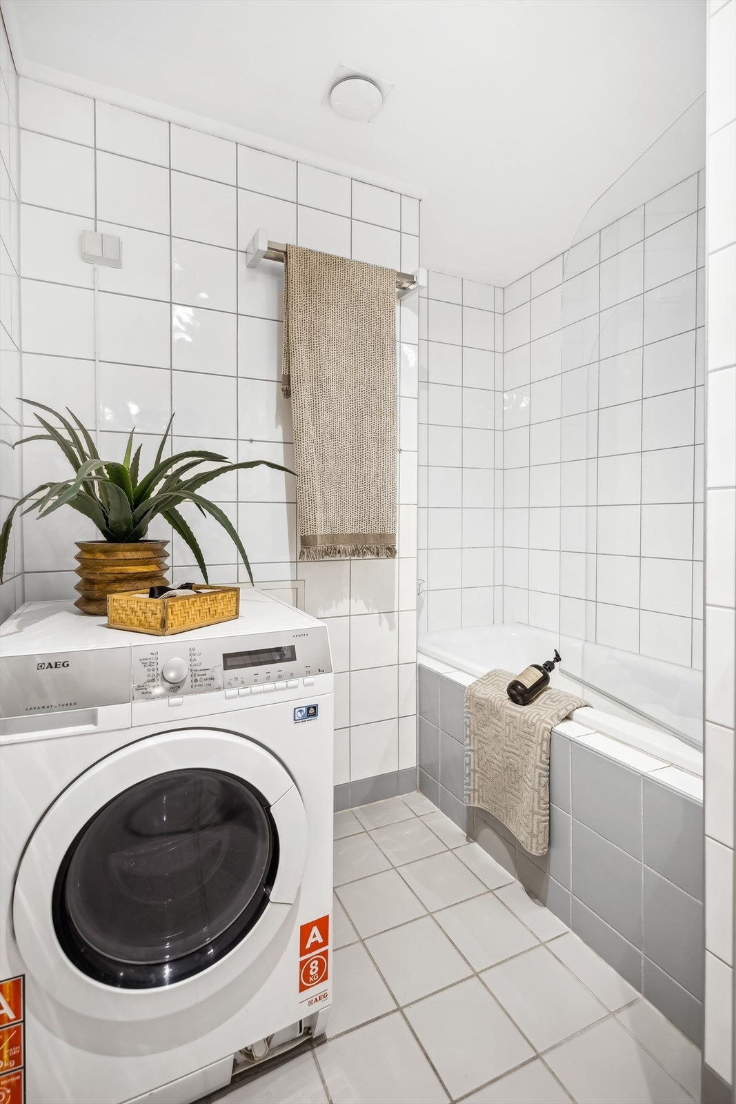 Flisalgt bad bestående av vegghengt wc, servant, speil m/overlys, innfliset badekar. Galleribilde