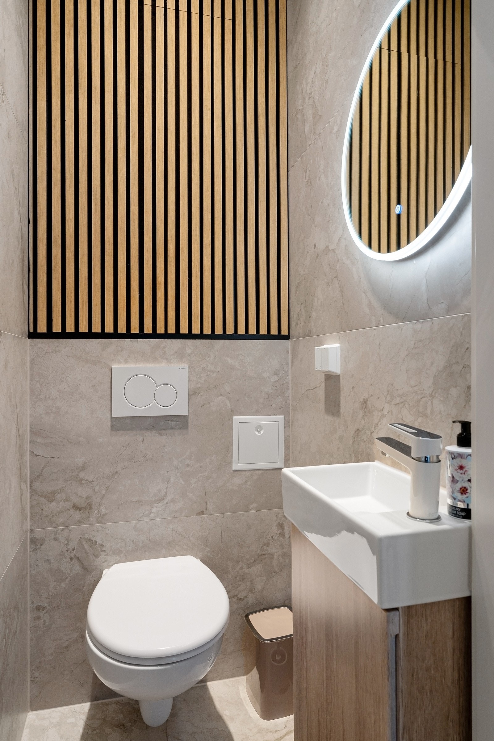 Pent og separat toalettrom som består av vegghengt toalett, servant over innredning og speil. Galleribilde