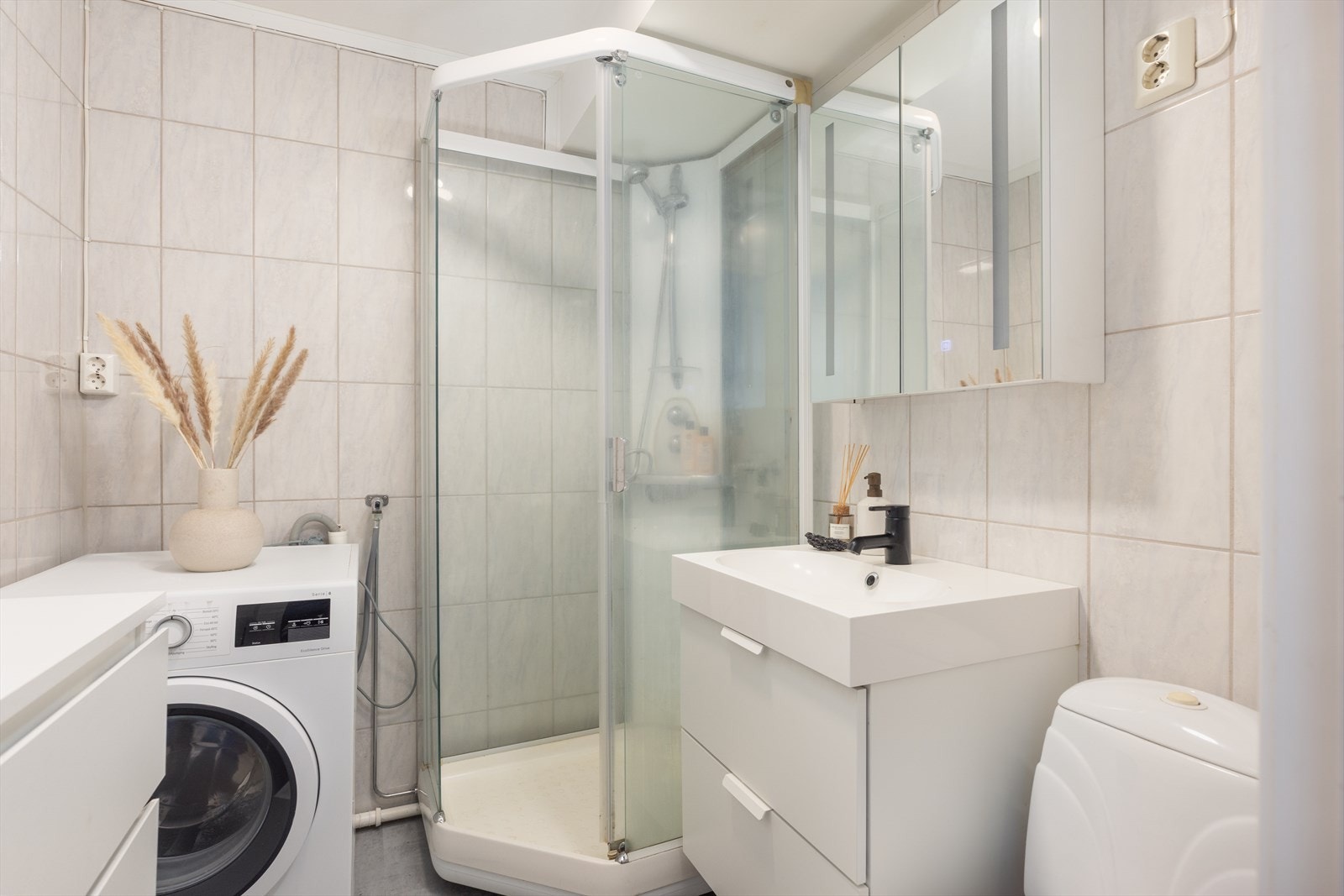 Badet består av gulvstående toalett, servant med skuffer og dusjkabinett med glassvegger Galleribilde