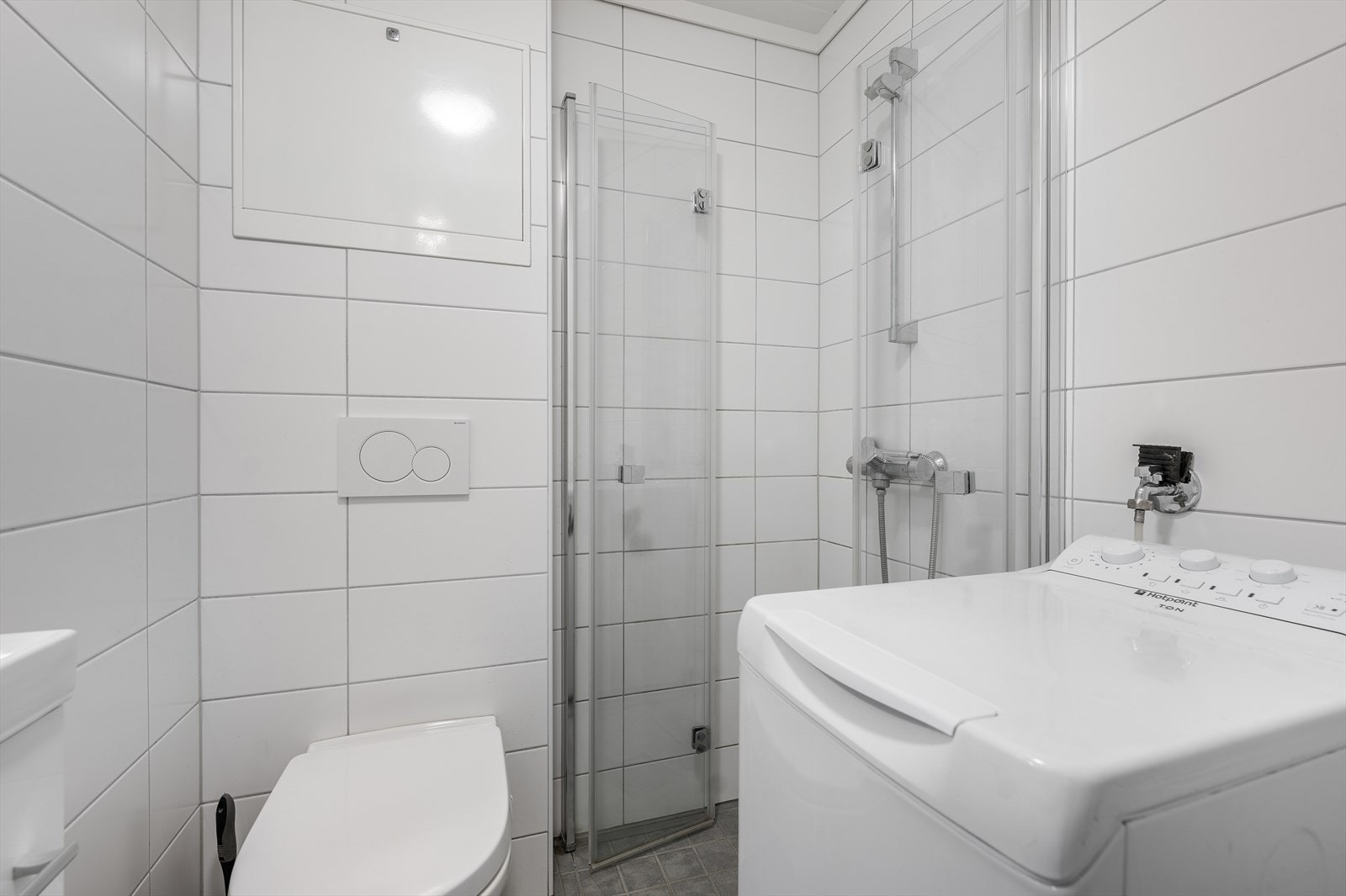 Baderommet er utstyrt med veggmontert toalett, opplegg for vaskemaskin, glassdører til dusjnisje samt dusjgarnityr. Galleribilde
