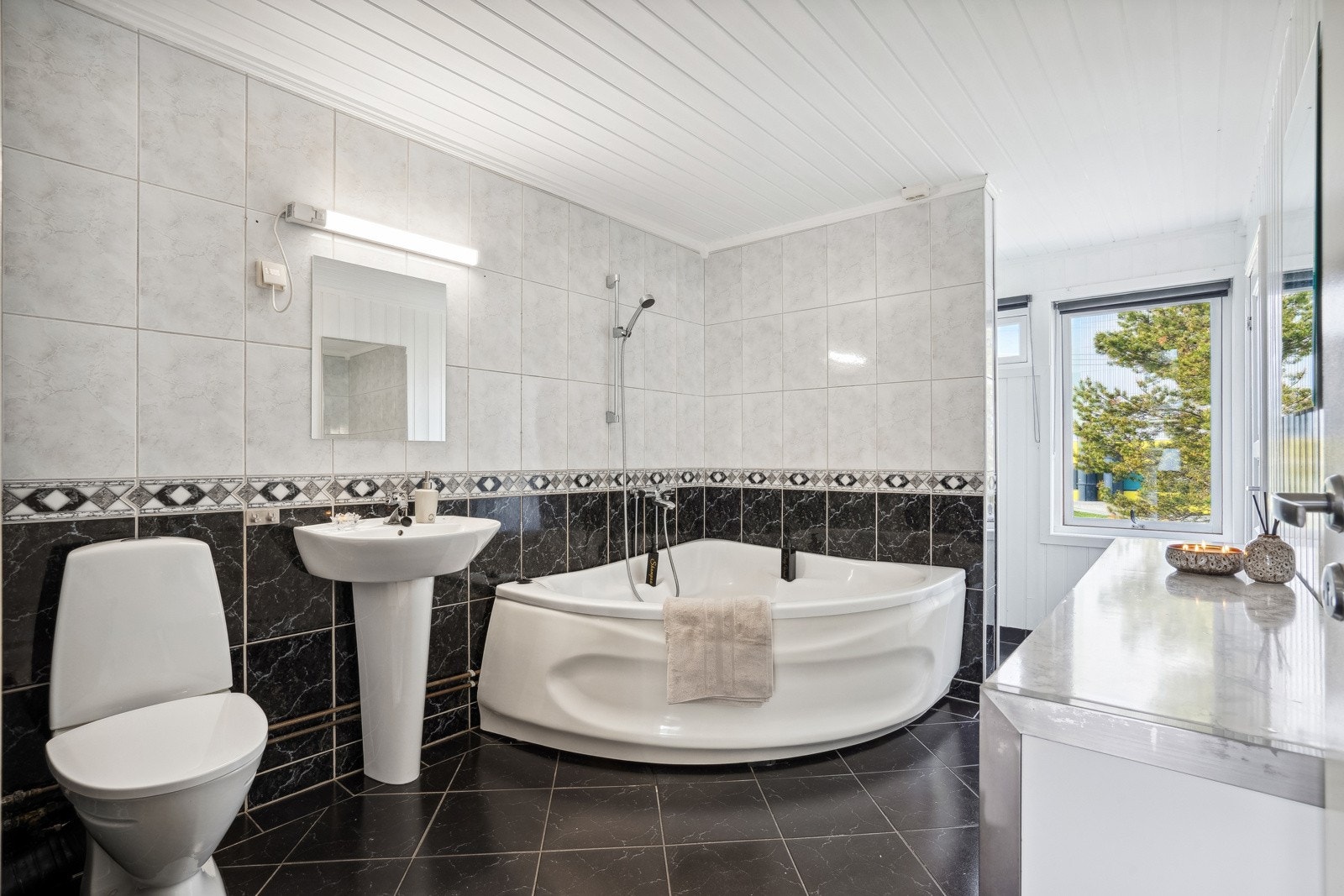 Badet måler romslige 9,5 kvm og er innredet med hjørnebadekar, en pen og moderne innredning samt toalett. Galleribilde