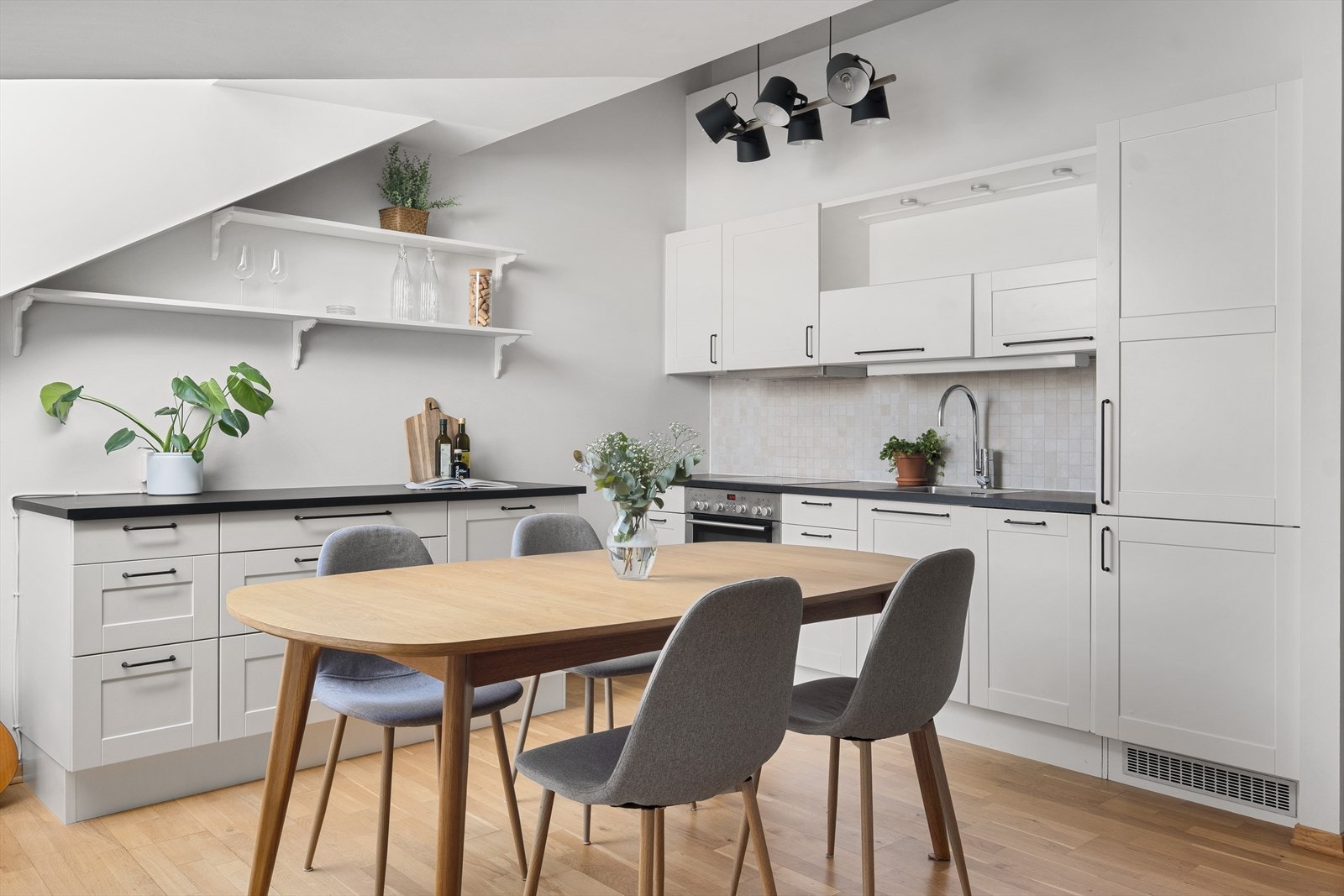 Kjøkkeninnredning med hvite enkeltspeil fronter, benkeplate i laminat med kum og ett-greps blandebatteri. Galleribilde