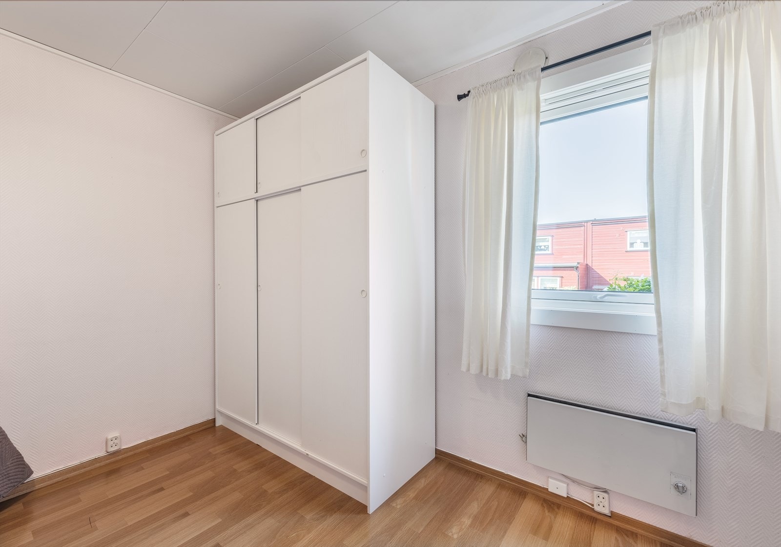 Videre er det et garderobeskap og rommet oppvarmes ved en panelovn under vinduet. Galleribilde