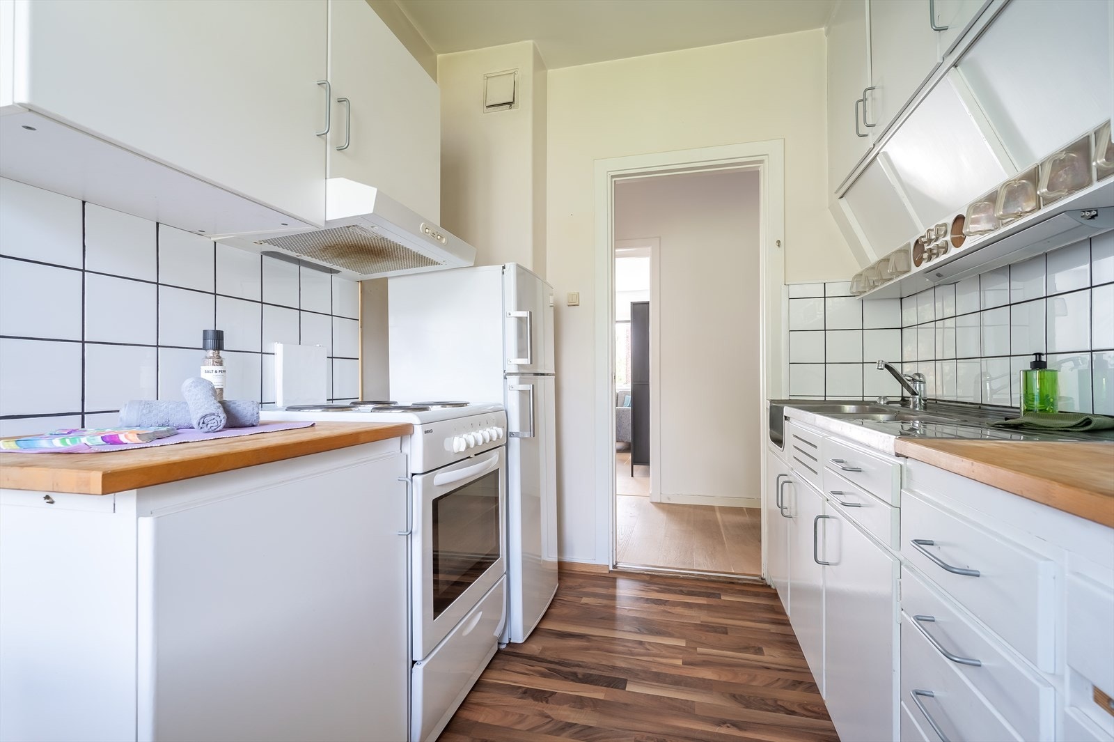 Innredningen består av eldre hvite fronter, heltre benkeplate med vaskekum av stål og frittstående hvitevarer. Galleribilde