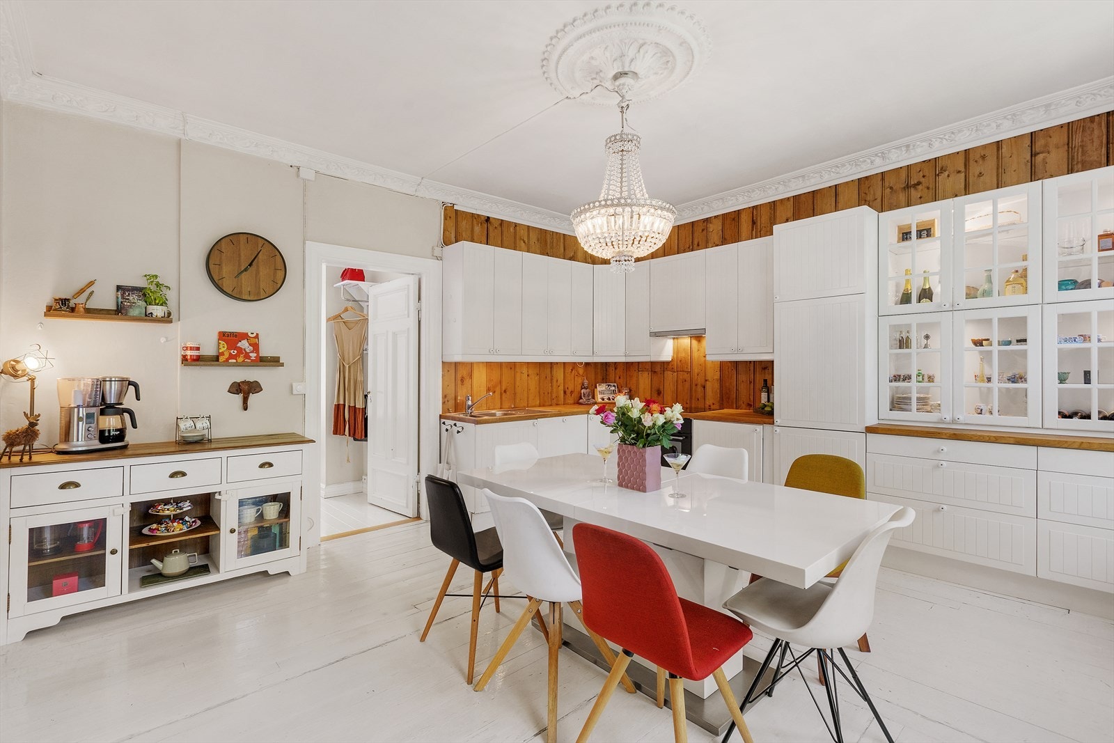 Kjøkkenet er smakfullt innredet med moderne skapfronter, trepaneler som gir varme og sjarm, samt en åpen løsning mot spiseplassen. Lysekronen i taket skaper et eksklusivt uttrykk Galleribilde