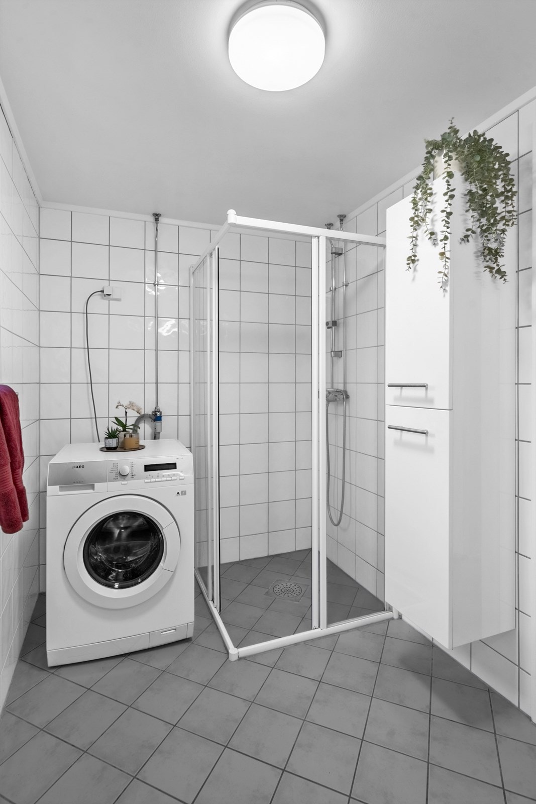 Badet er flislagt bad med varmekabler på gulv. Det er også 90x90 dusjhjørne med skyvedører og opplegg for vaskemaskin. Galleribilde