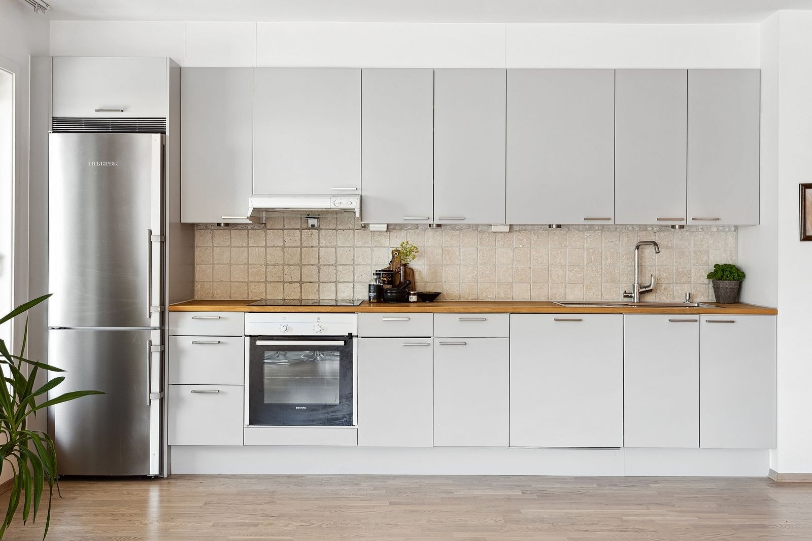 Stilrent kjøkken fra 2013 med integrerte hvitevarer som platetopp, stekeovn, oppvaskmaskin og frittstående kjøle-/fryseskap. Galleribilde