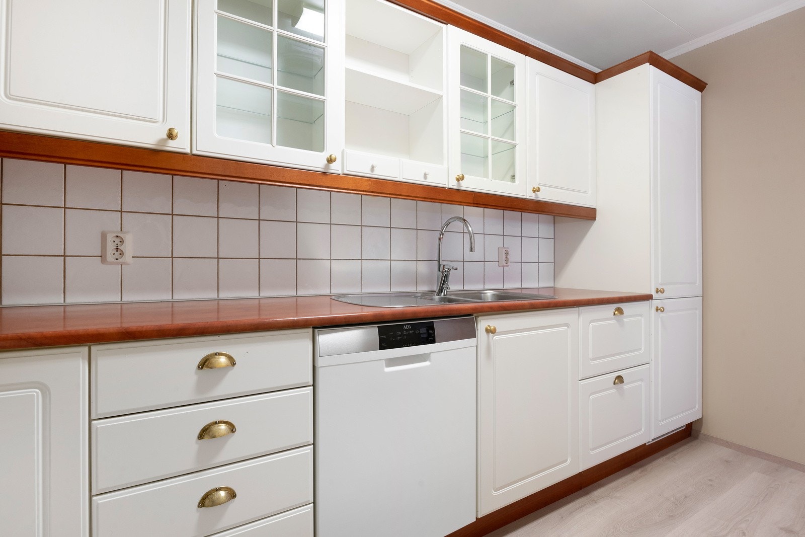 Innreiinga har kvite profilerte frontar, laminert benkeplate, integrert steikeomn/koketopp samt fryse- og kjøleskap Galleribilde