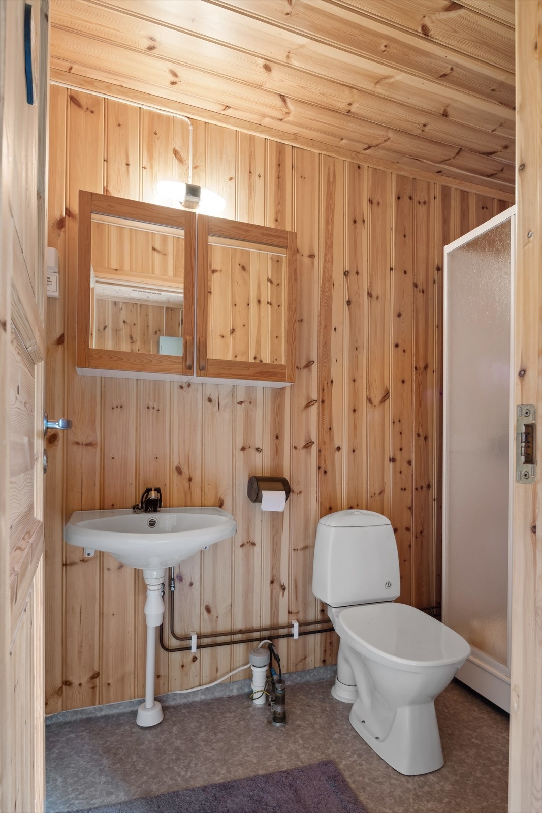 Bad med servant på vegg, gulvmontert WC og dusjkabinett. Galleribilde