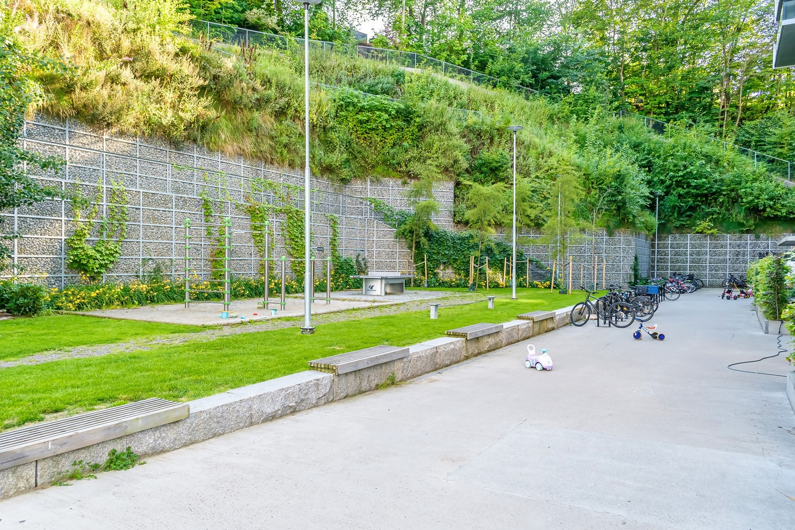 Hyggelig bakgård med lekestativer, planter og sittegrupper. Galleribilde