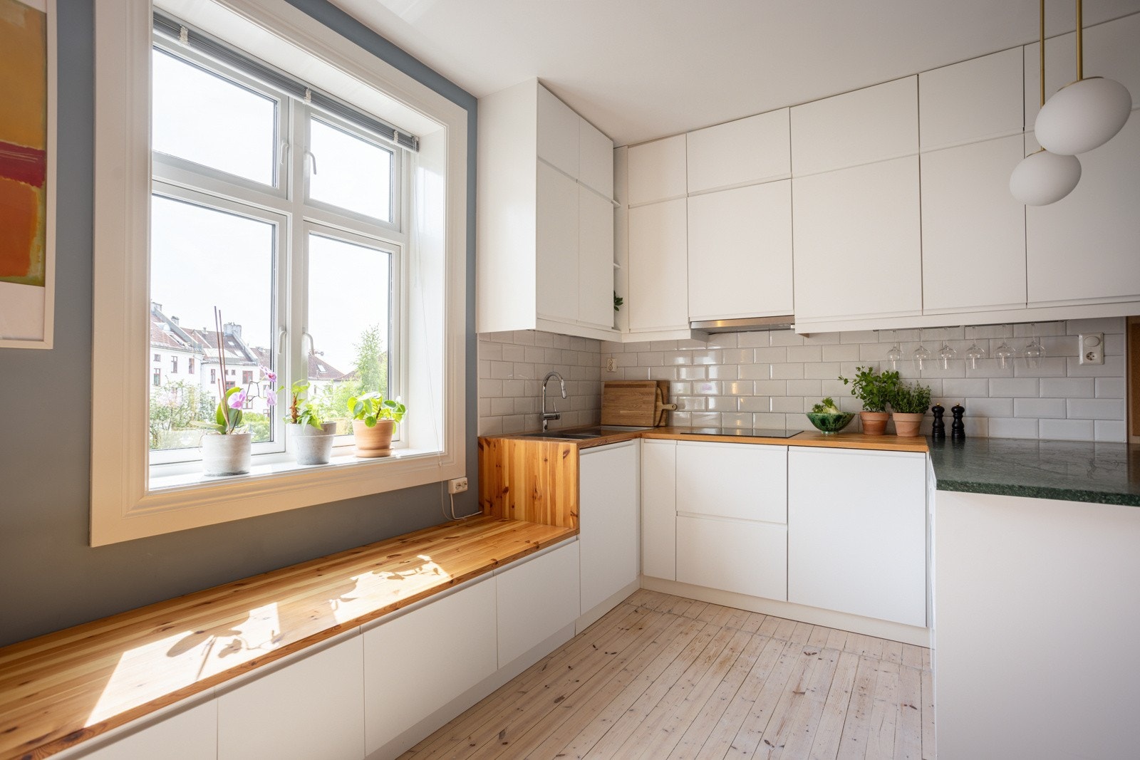 Innredningen har hvite, glatte fronter og benkeplate av tre med nedfelt oppvaskkum. Både fint og praktisk med lekre fliser i benkeryggen og belysning under de takhøye overskapene. Galleribilde