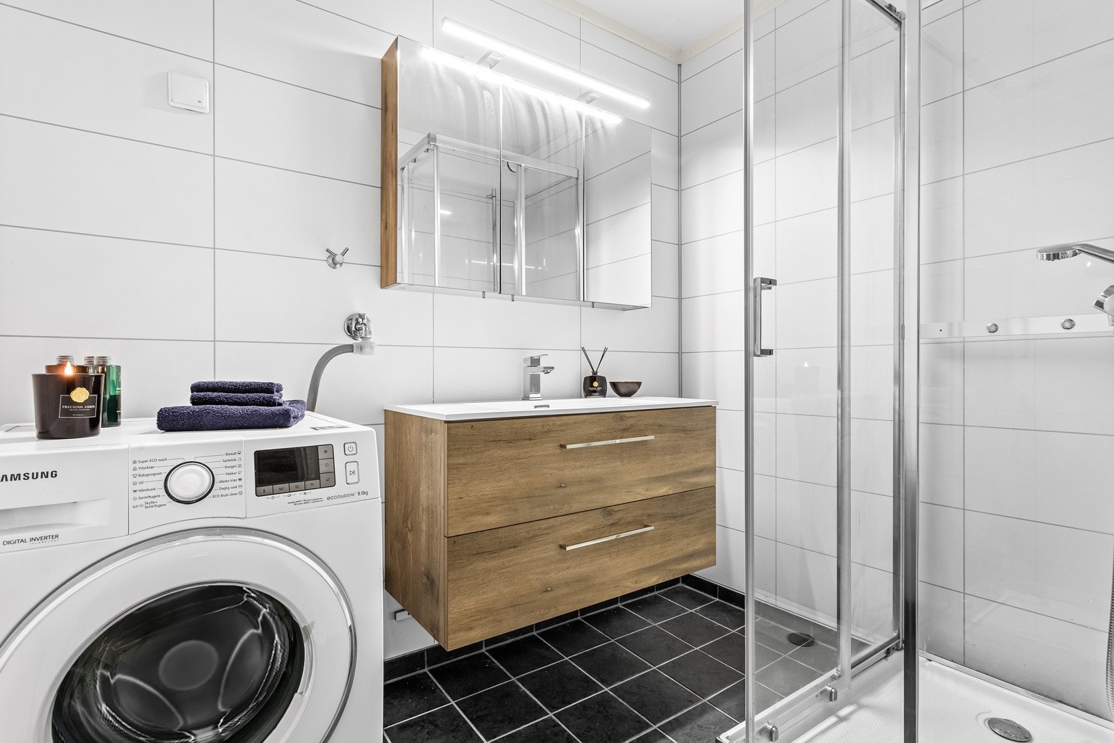 Pent flislagt baderom med opplegg for vaskemaskin og tørketrommel, ny servantinnredning og nyere dusjkabinett. Galleribilde
