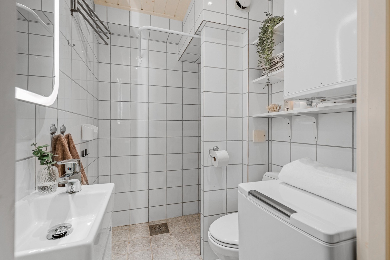 Flislagt bad på 3 kvm utstyrt med baderomsinnredning, klosett og dusjhjørne. Varmtvannstanken er plassert på badet. Galleribilde