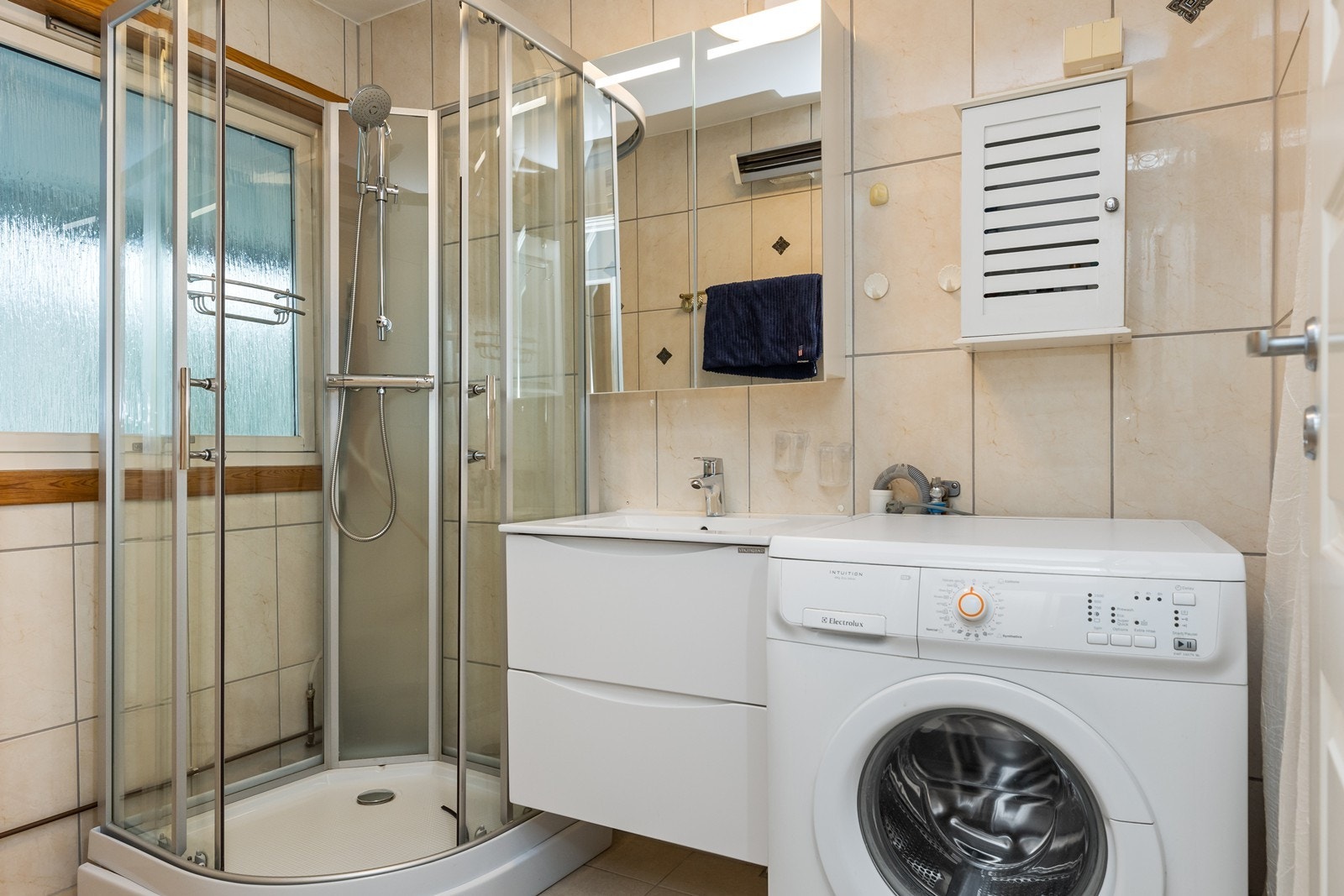 Badet har fliser på vegger og gulv. Her er det også opplegg til vaskemaskin Galleribilde