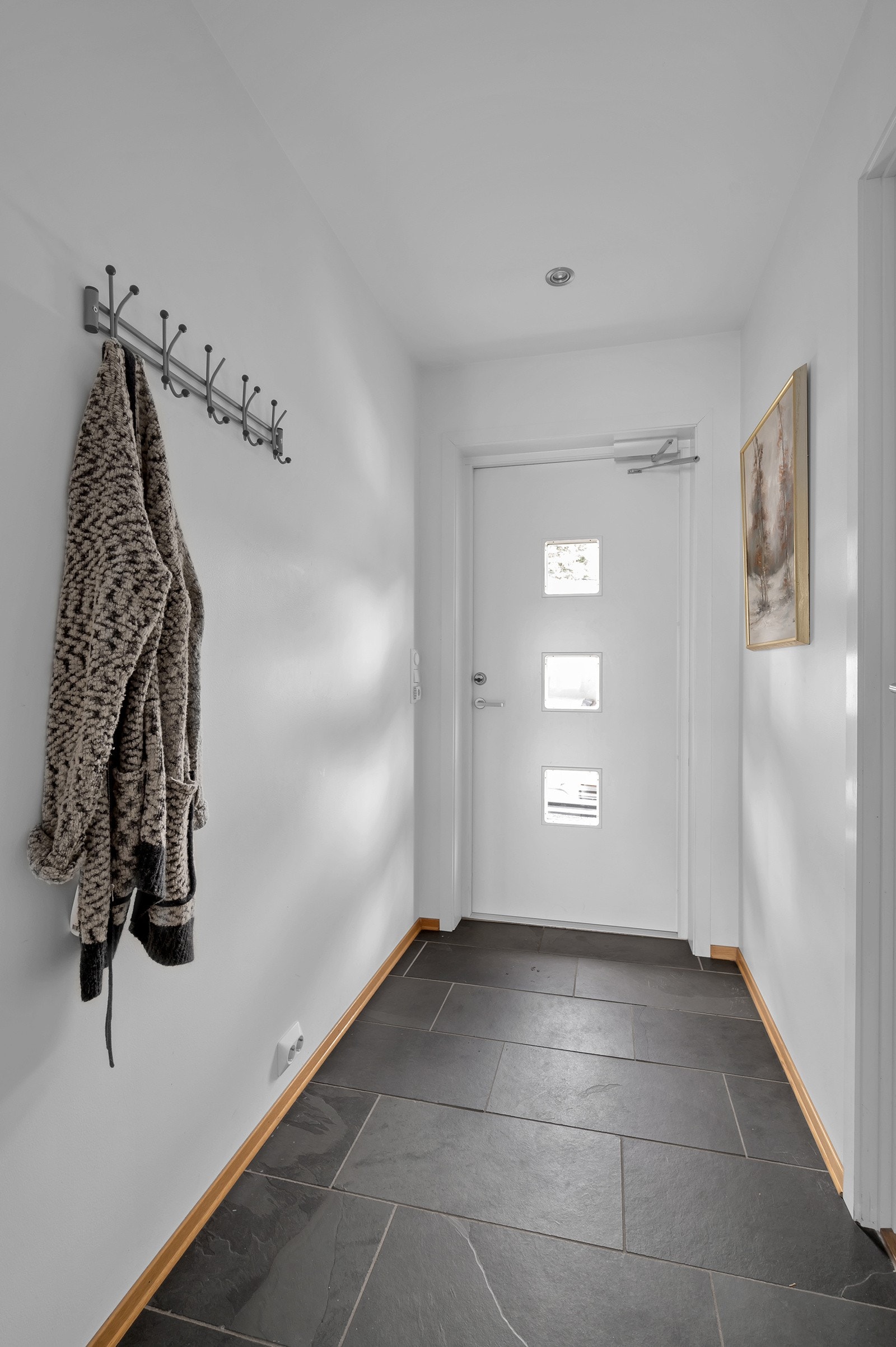 Lys og flislagt inngangsparti med varmekabler i gulv og spotdownlights i tak. Galleribilde