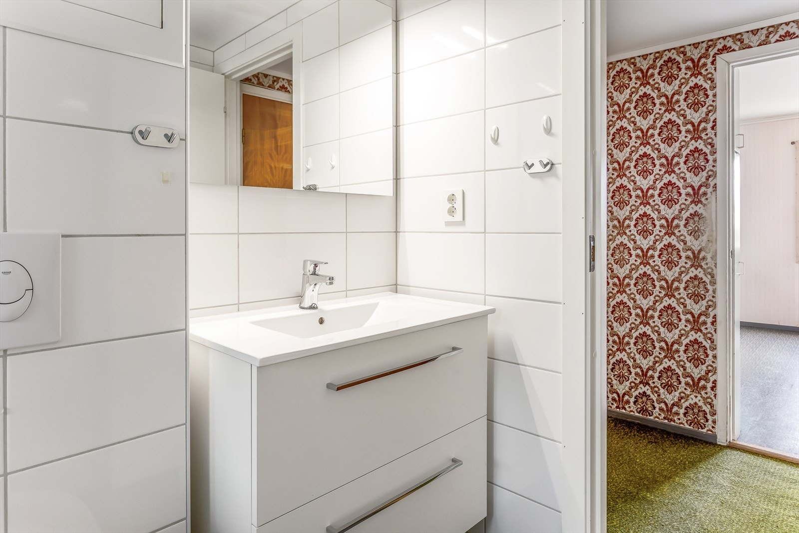 Badet inneholder vegghengt toalett, helstøpt servant, skuffer under servant med slette fronter, dusjdører i klart glass og fordelerskap til rørsystemet Galleribilde