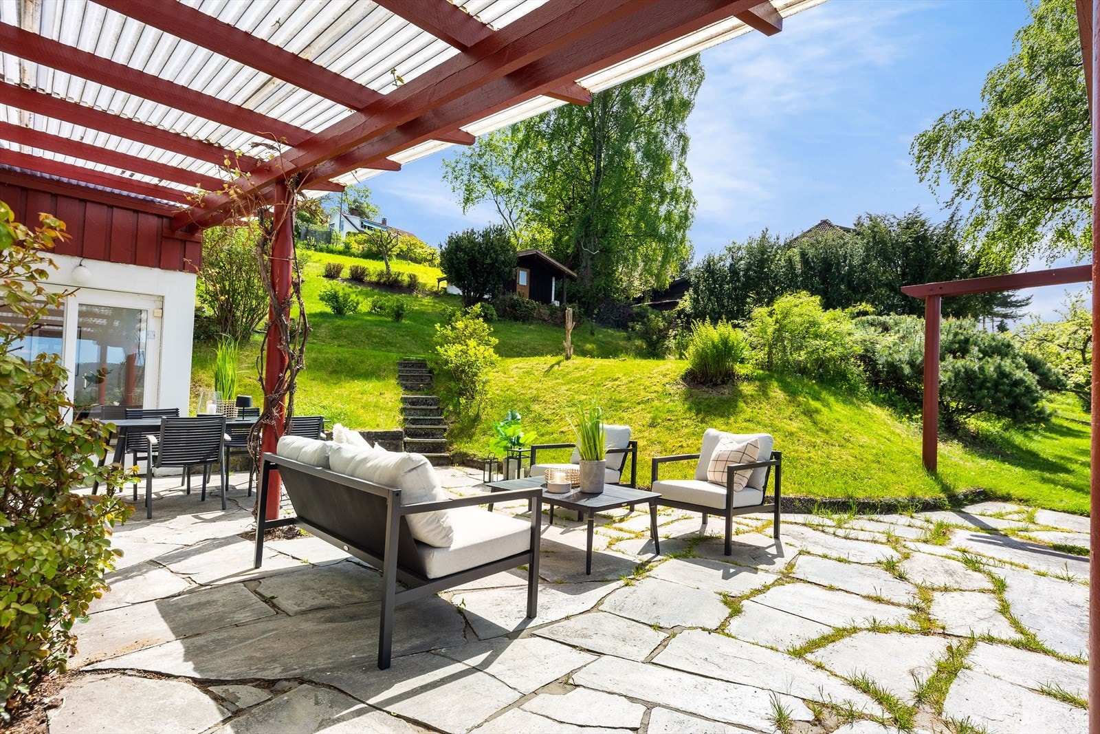 Overbygget pergola med god plass til flere sittegrupper i dette hyggelige uteområdet Galleribilde