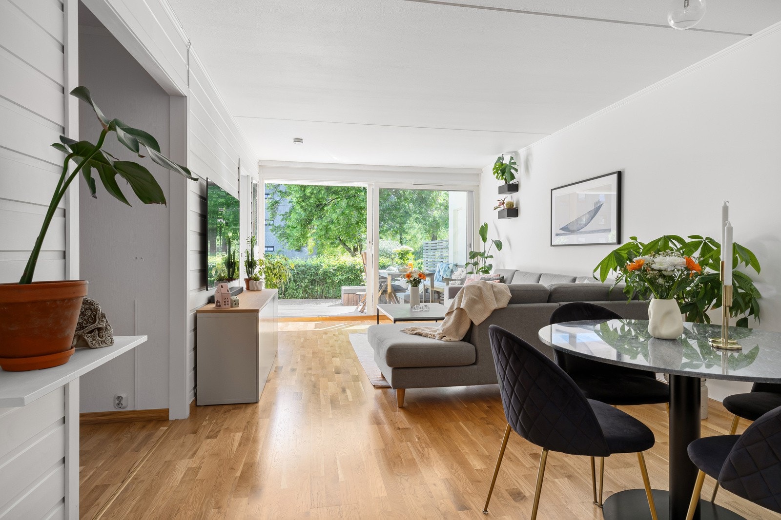 Stuen bades i dagslys fra vindusfasade mot sydvest, med skyvedør ut til terrassen. Galleribilde