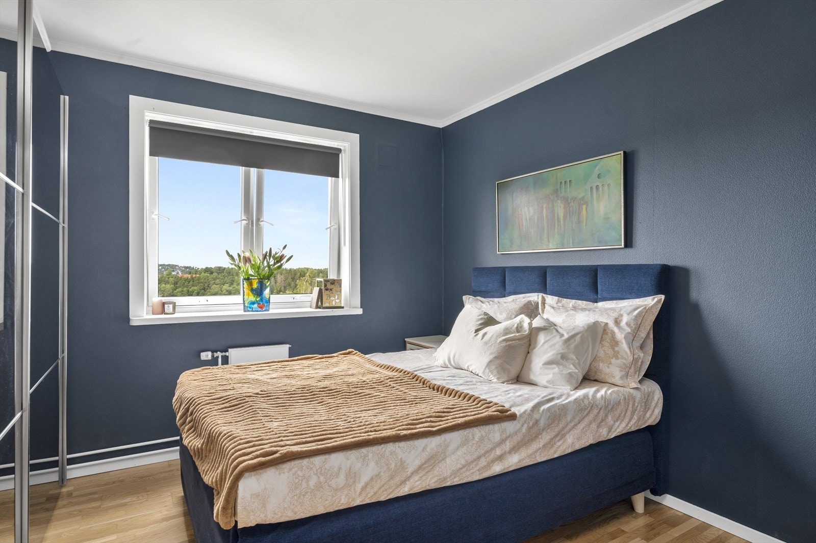 Leiligheten har et soverom malt i moderne, mørk blåfarge. Galleribilde