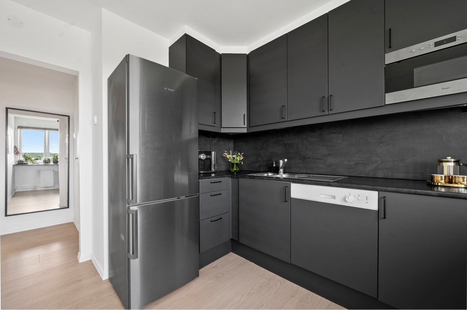 Lekkert og moderne kjøkken med skuffer og takhøye skap med mørke fronter. Galleribilde