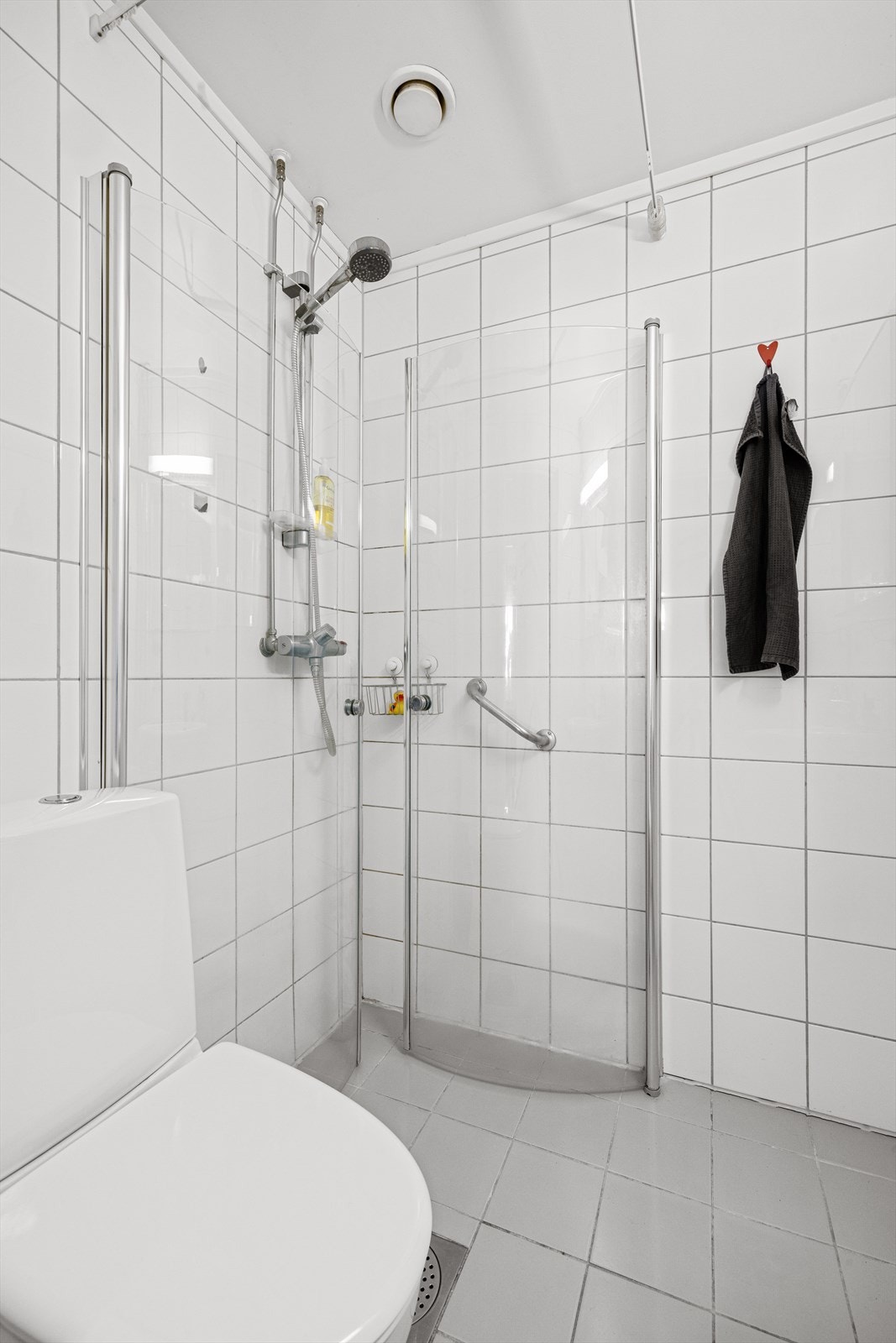 Badet er pent flislagt med hvite fliser på vegg og grå fliser på gulv med varmekabler Galleribilde