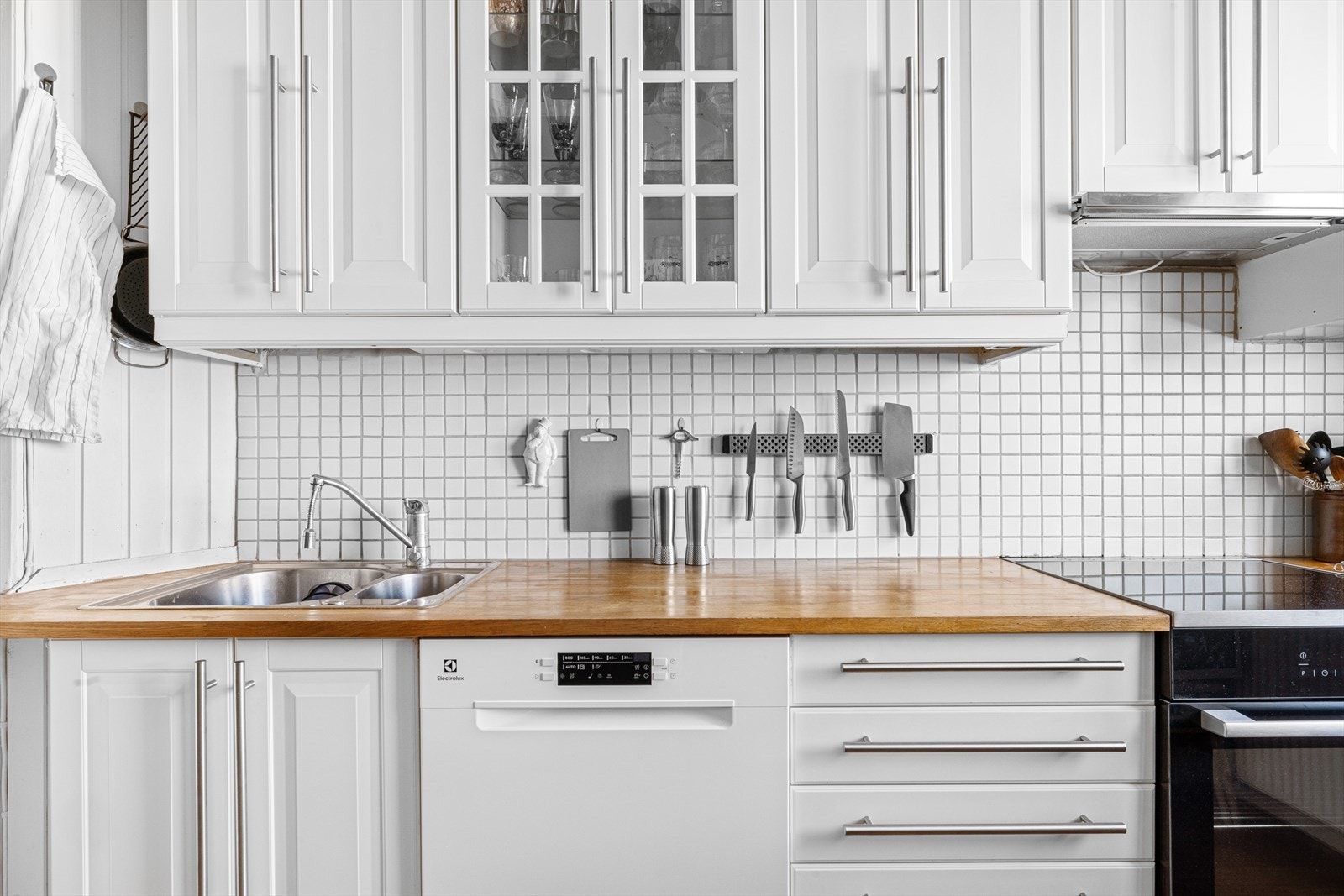 Videre består kjøkkenet av en eldre kjøkkeninnredning med hvitmalte/profilerte fronter, lys under overskap og lyse, laminat benkeplater. Det er også opplegg for vaskemaskin Galleribilde