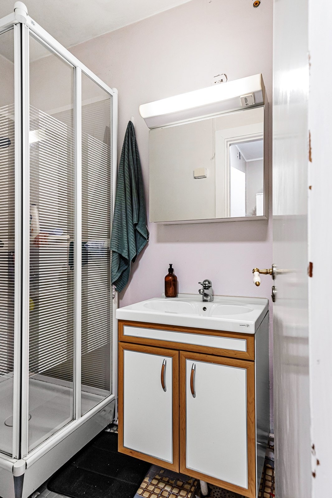 Rommet er innredet med blant annet dusjkabinett, servantinnredning med skap og speilskap med lys. Galleribilde