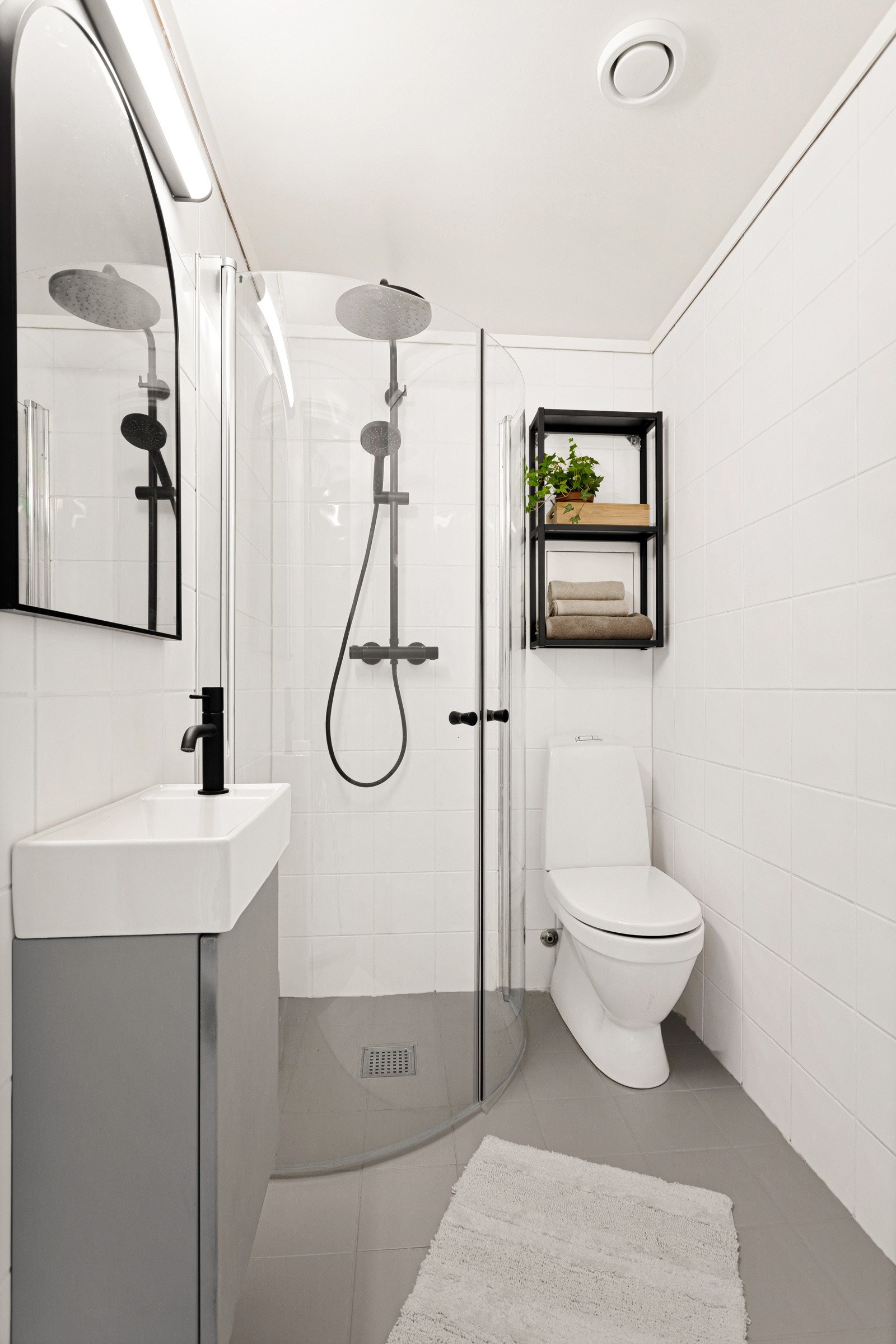 Flislagt baderom med nytt toalett, innredning med servant, dusjhjørne med glassdører og opplegg til vaskemaskin. Galleribilde