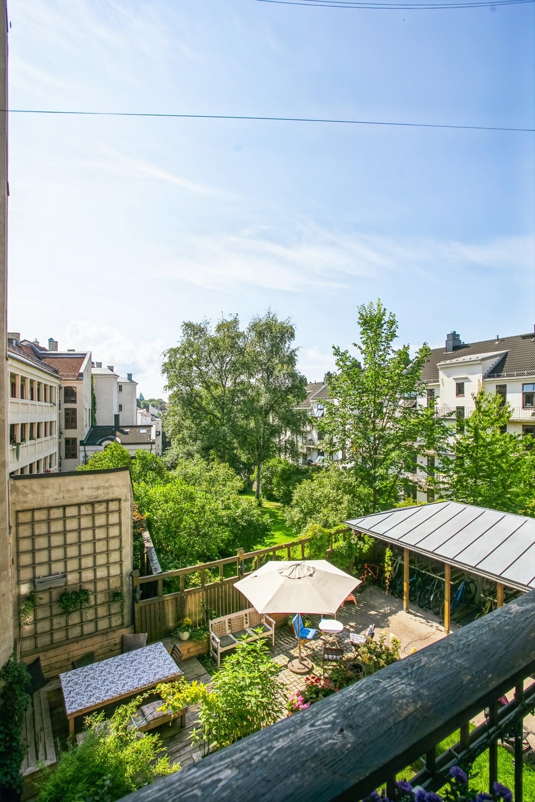 Utsikt fra balkongen over en frodig felles bakgård Galleribilde