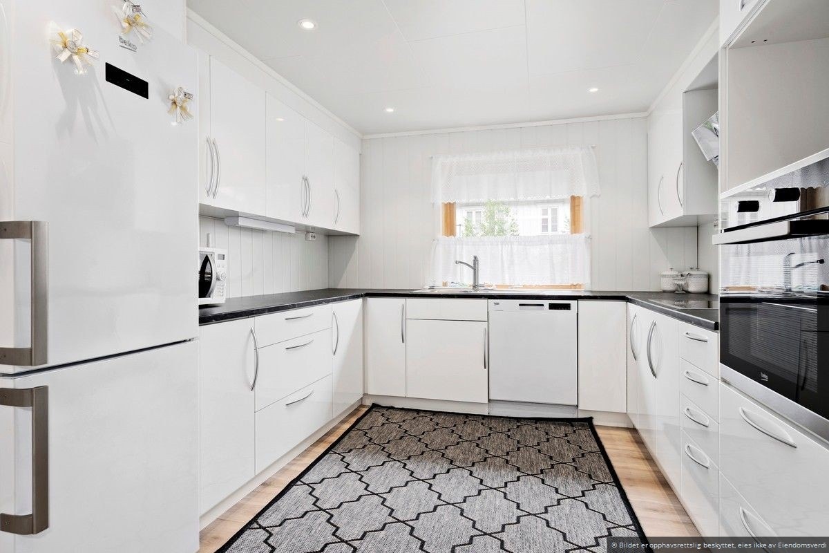 Kjøkkenet byr på rikelig med skap- og benkeplass. Avtrekkshette med sort glassfront og avløp ført ut gjennom yttervegg. Innredningen er fra Nygård kjøkken og ble montert i 2017. Integrerte hvitevarer (komfyr og platetopp) medfølger. Galleribilde