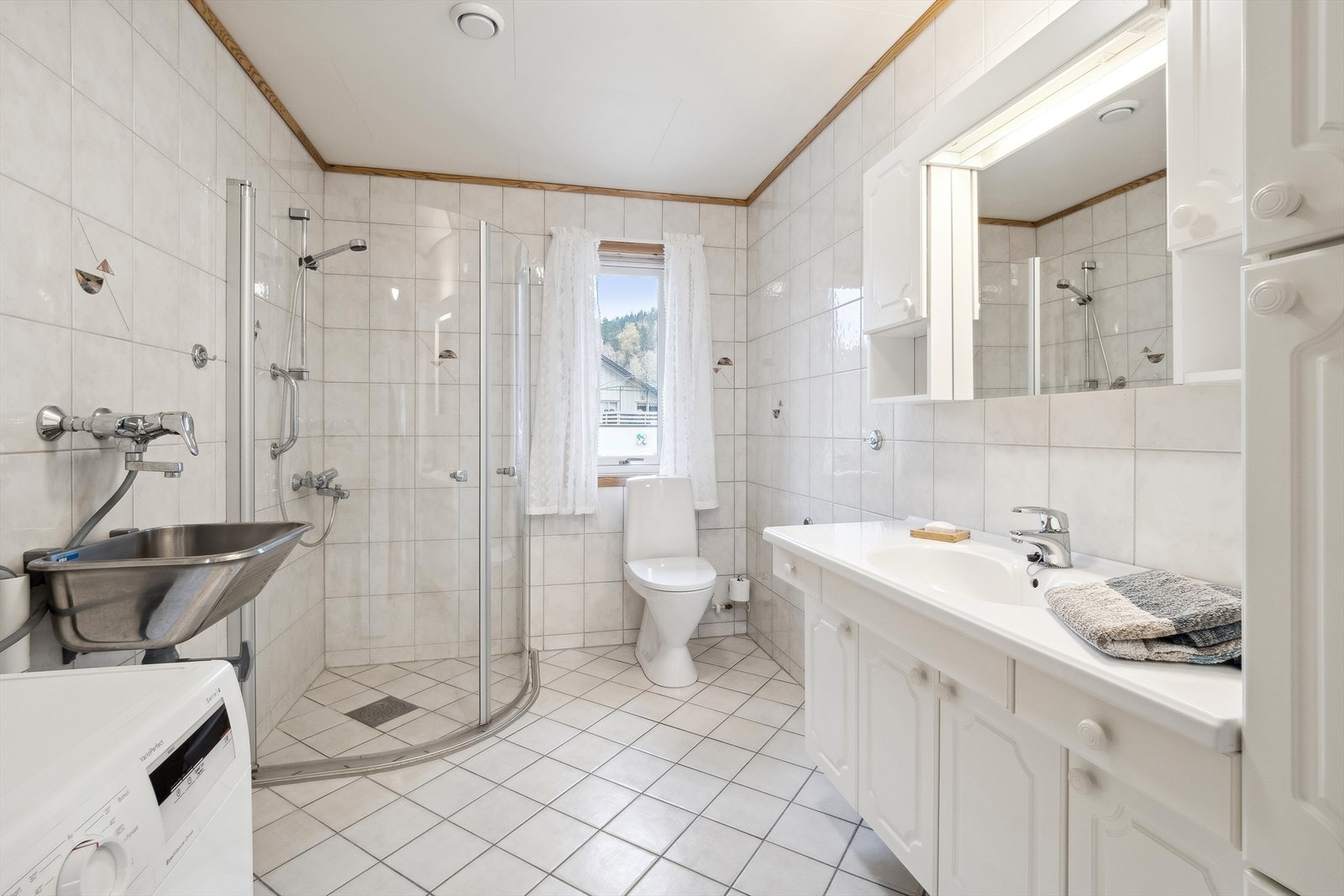 Badet i leiligheten har flislagte gulv med gulvvarme, og det er flis på veggene Galleribilde
