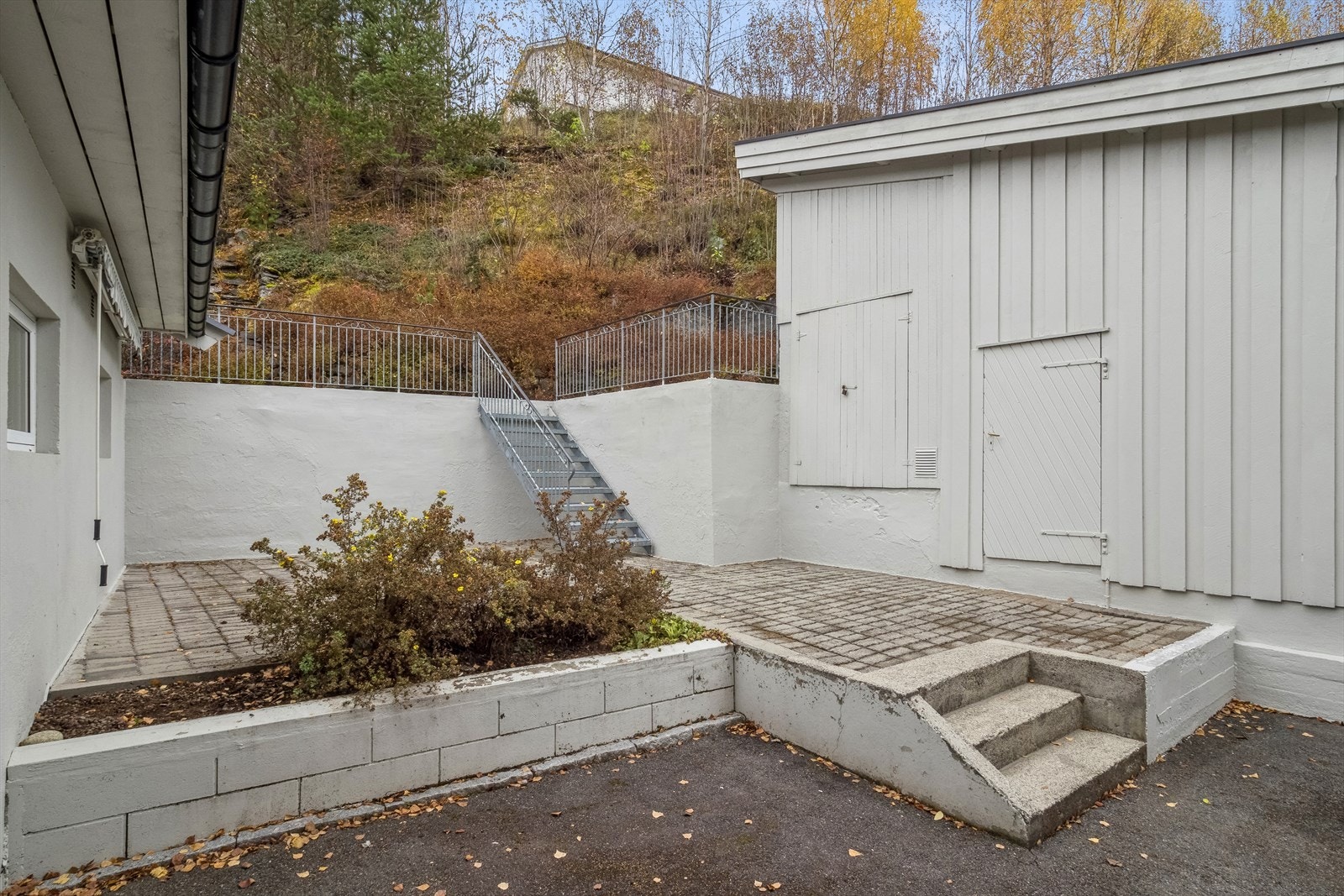 Fin skjermet uteplass med trapp opp til grøntareal og uthus. Galleribilde