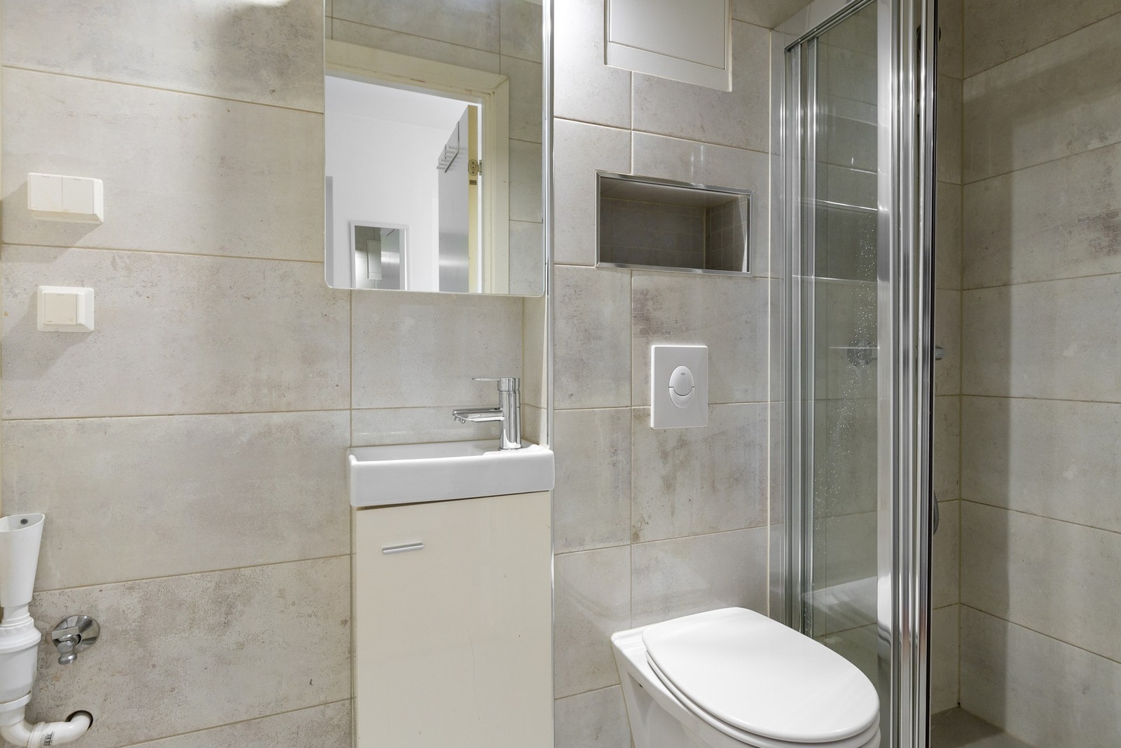 Baderom med dusj, vegghengt toalett og opplegg til vaskemaskin. Galleribilde