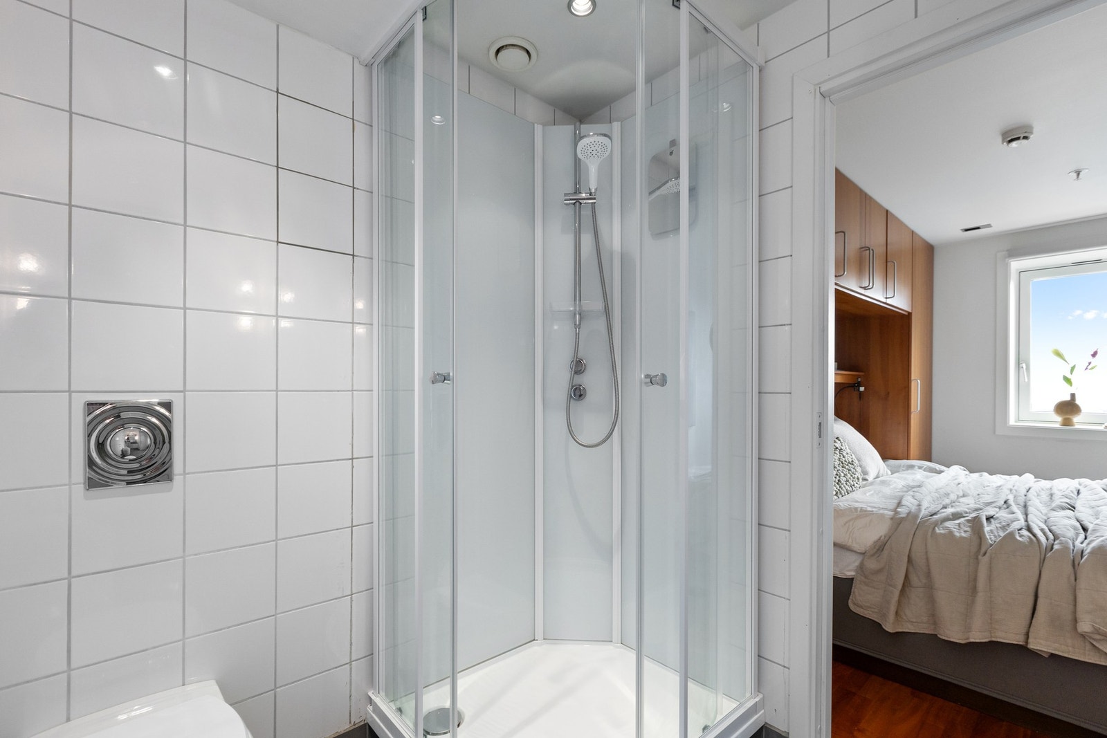 Det er vegghengt toalett med innebygget sisterne og dusjkabinett på baderom. Galleribilde