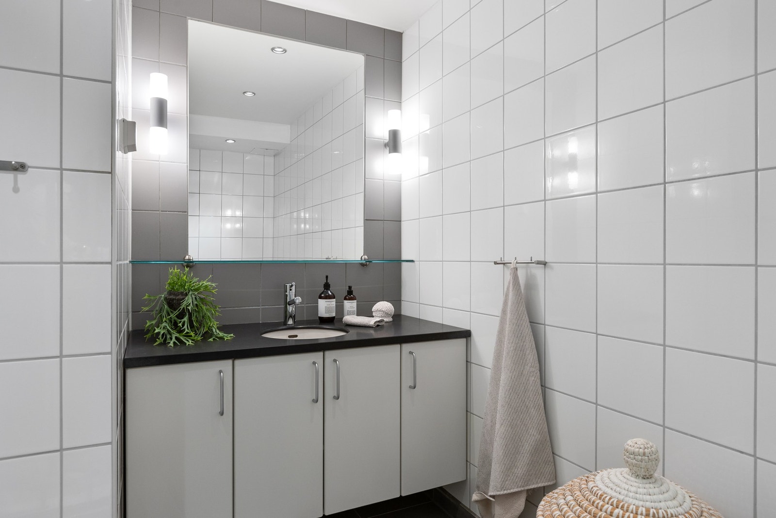 Baderommet i 13. etasje har stort speil med lys og skap under servant. Galleribilde